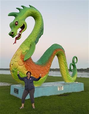 Woman flexing in front of a colorful serpent statue
