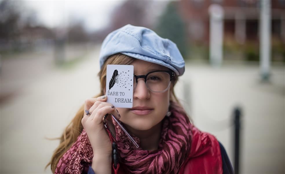 Woman holding a card over her right eye,