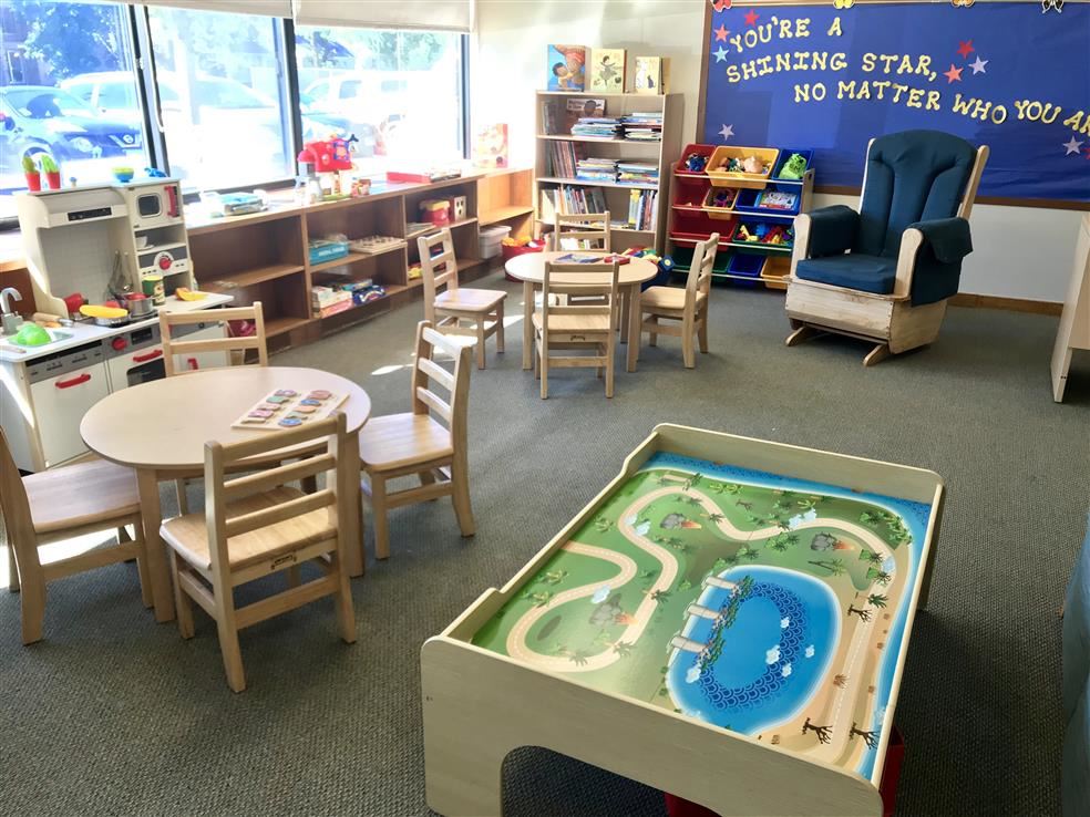 Color photograph showing a colorful room with children's tables and chairs, toys, and books.