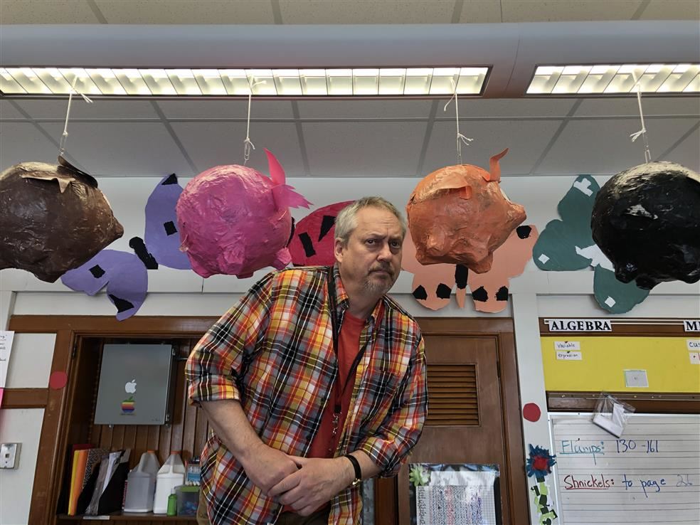 Mr. Andersen by his class's "When Pigs Fly" art project