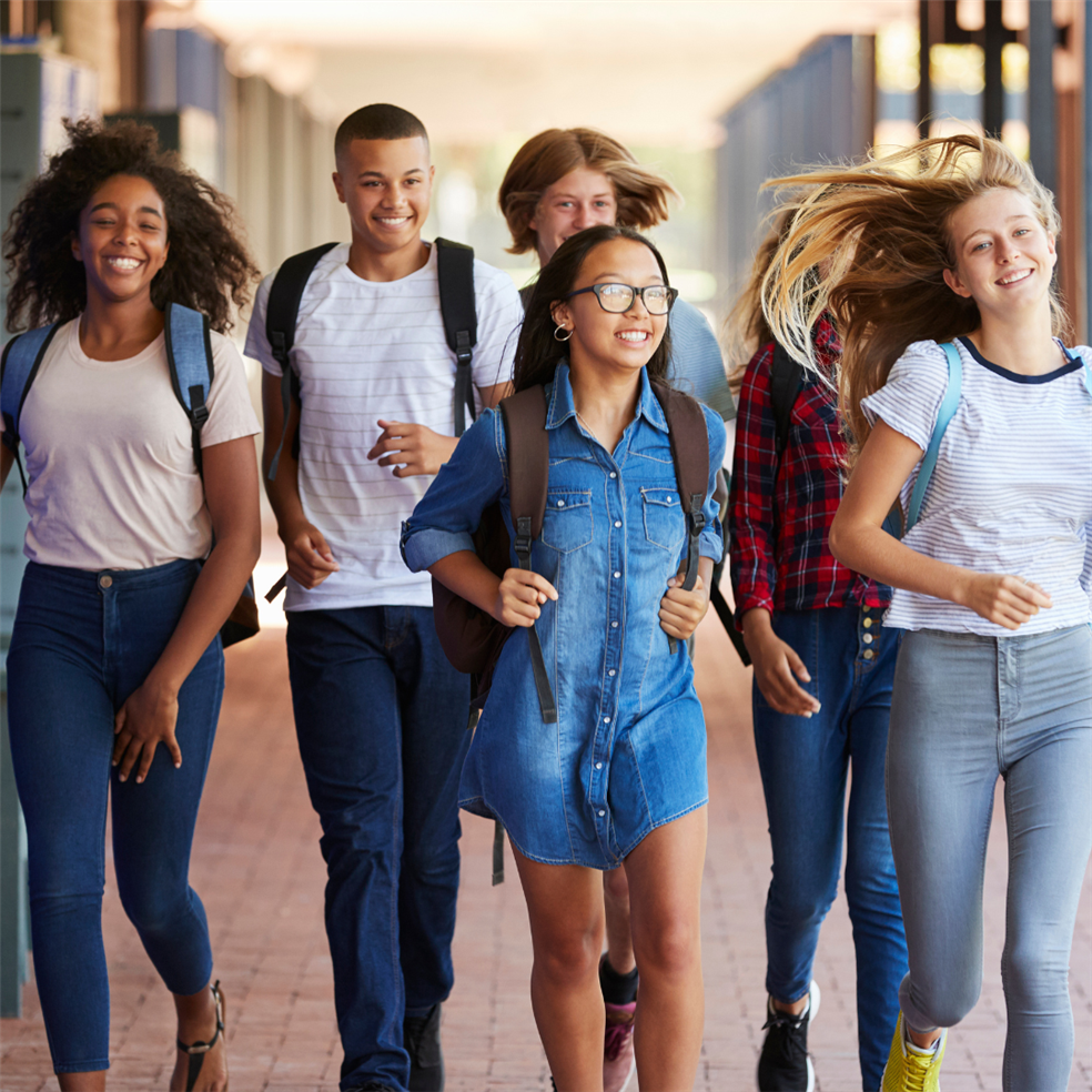 Smiling teenage students walking down the hallway in school.