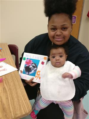 Here is a student displaying her homemade baby book, before reading it to her baby. 